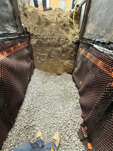 Foundation waterproofing trench prepared with membrane and clean gravel along the exterior wall