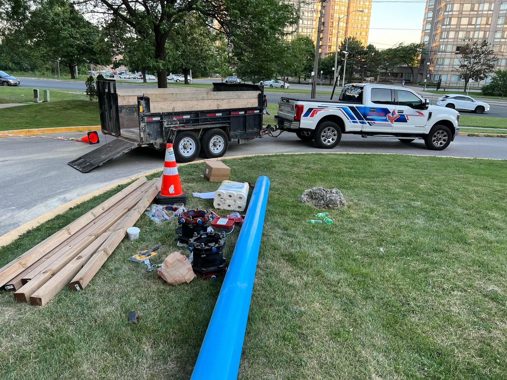 Service truck, trailer, and blue replacement pipe staged before a water-line replacement job