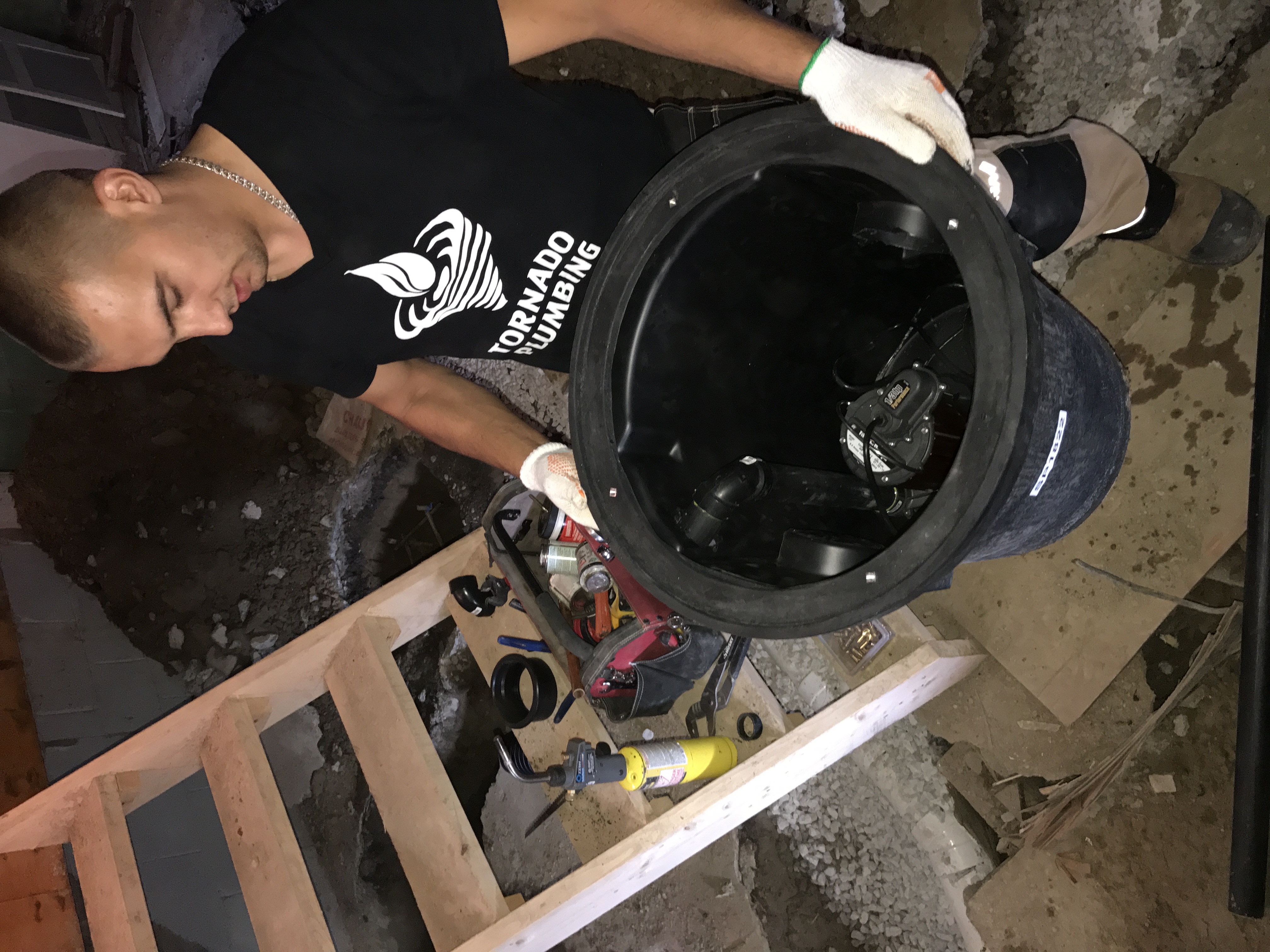 Technician holding a sump basin with pump components fitted inside before installation