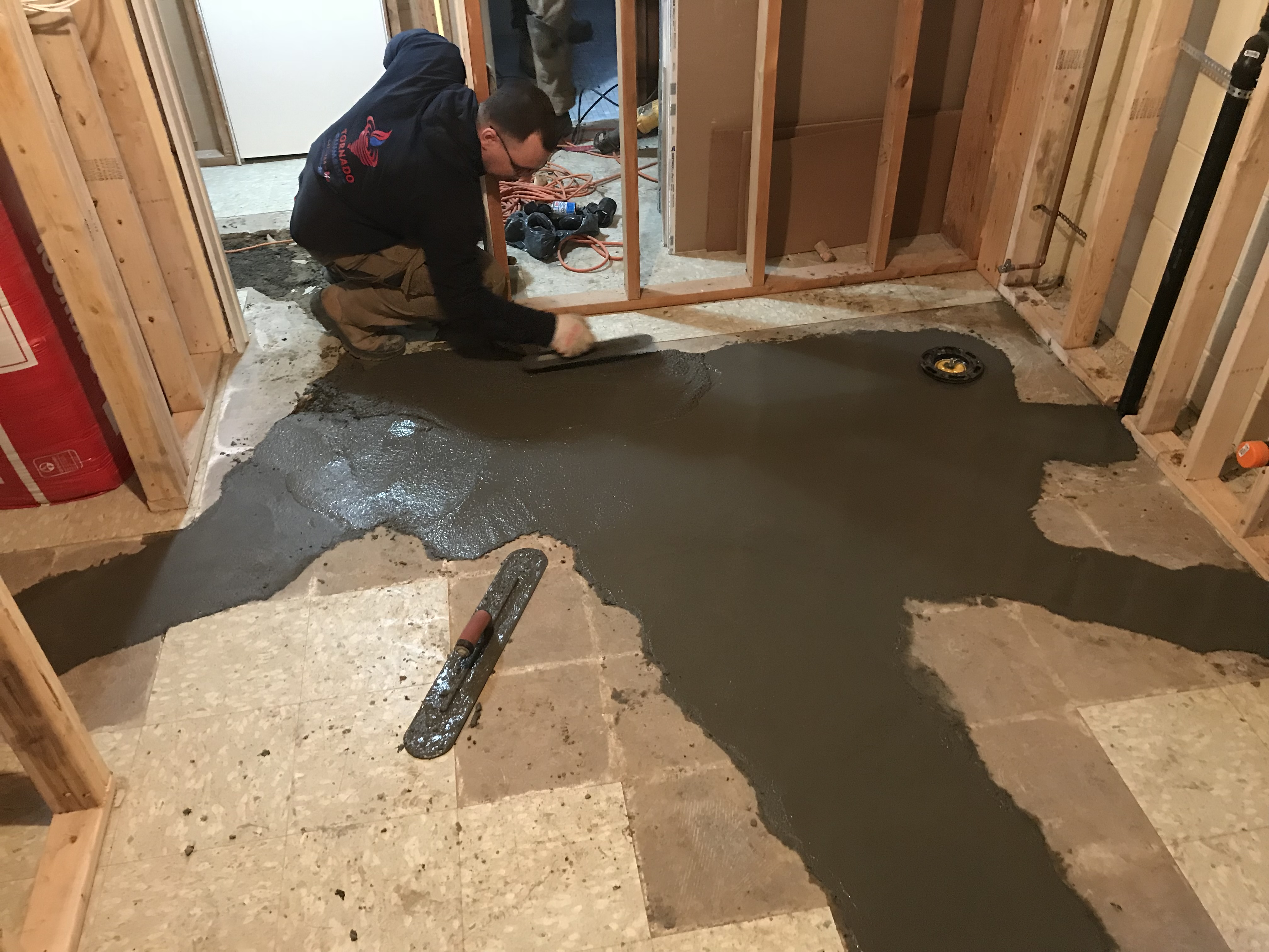 Fresh concrete patch around a basement floor drain after basement flood-protection plumbing work