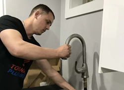 Technician working under a kitchen sink during an interior plumbing repair