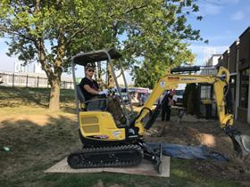 Mini excavator staged for exterior plumbing excavation work beside a home