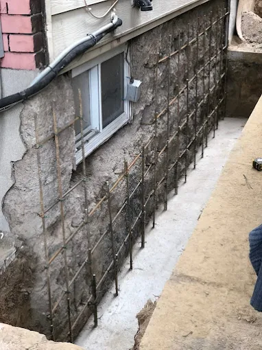 Foundation wall exposed and reinforced during exterior crack repair and waterproofing work