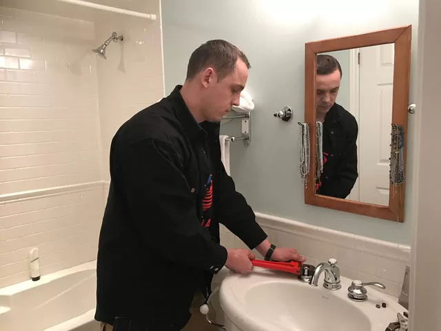 Technician working on a residential plumbing service call inside a finished bathroom